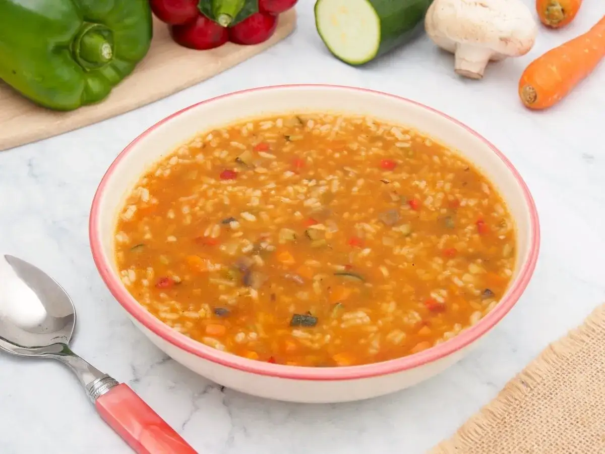 Un tazón de arroz con verduras, lleno de zanahoria, pimiento y calabacín.