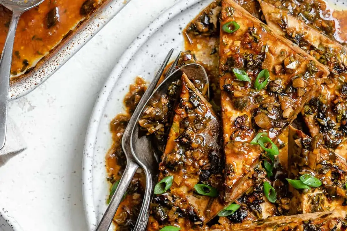 Tri&aacute;ngulos de tofu marinado cubiertos con una salsa sabrosa y cebolleta picada.