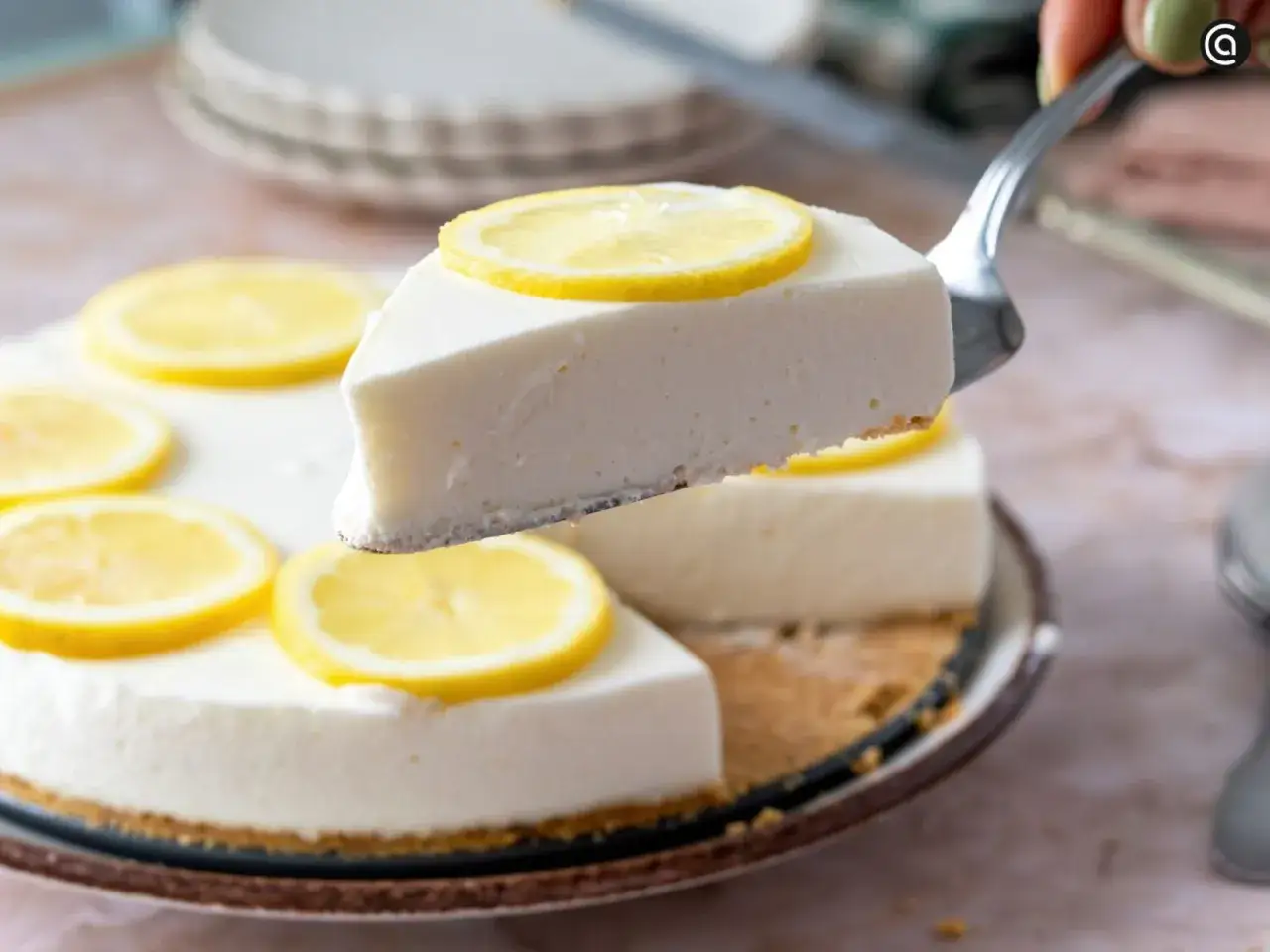 Una rebanada de tarta de lim&oacute;n sin horno, cremosa y decorada con rodajas de lim&oacute;n fresco.