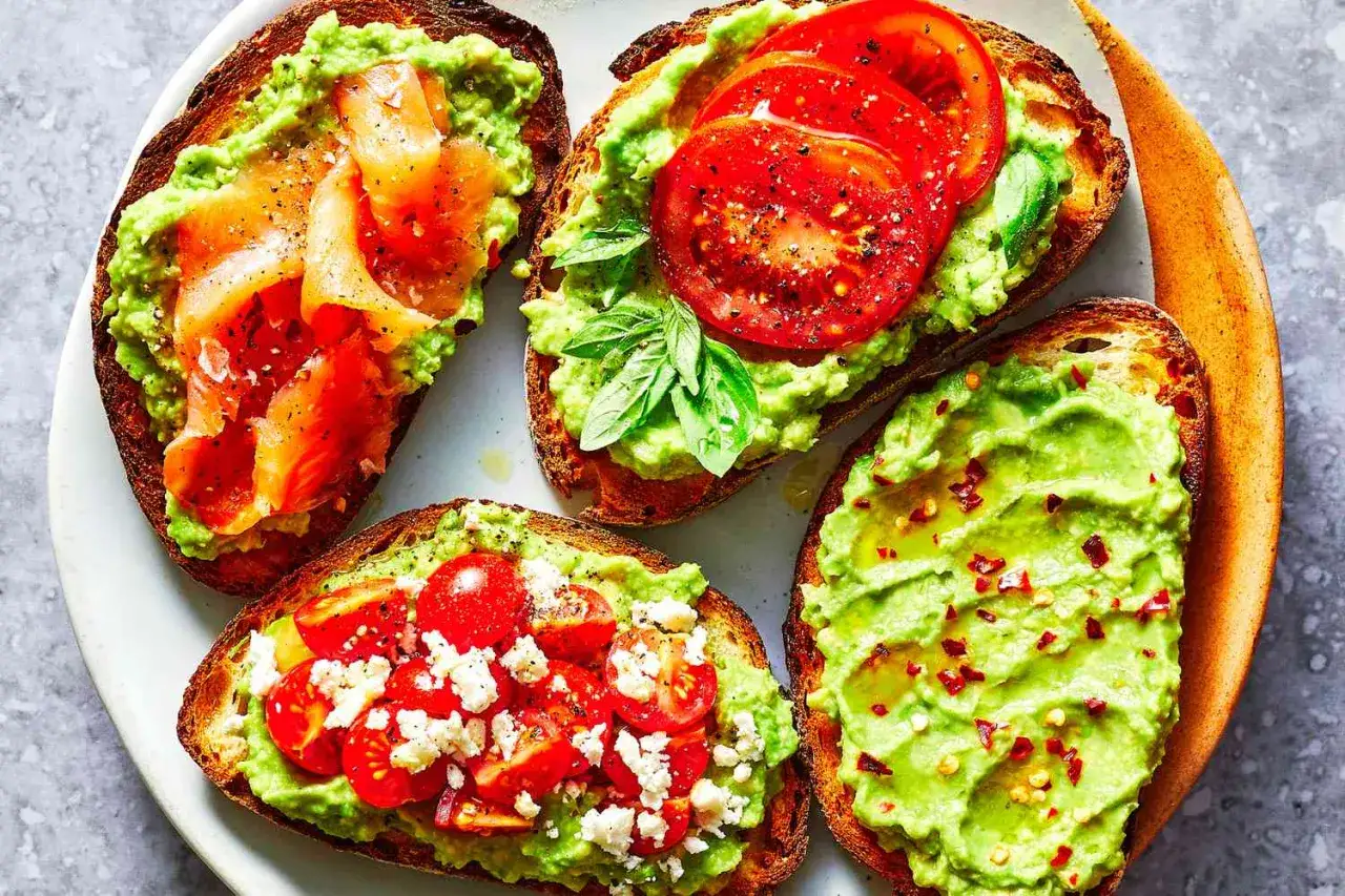 Cuatro tostas de aguacate para cenar: una con salm&oacute;n ahumado, otra con tomate y albahaca, una tercera con tomate y queso feta, y la &uacute;ltima con chile.