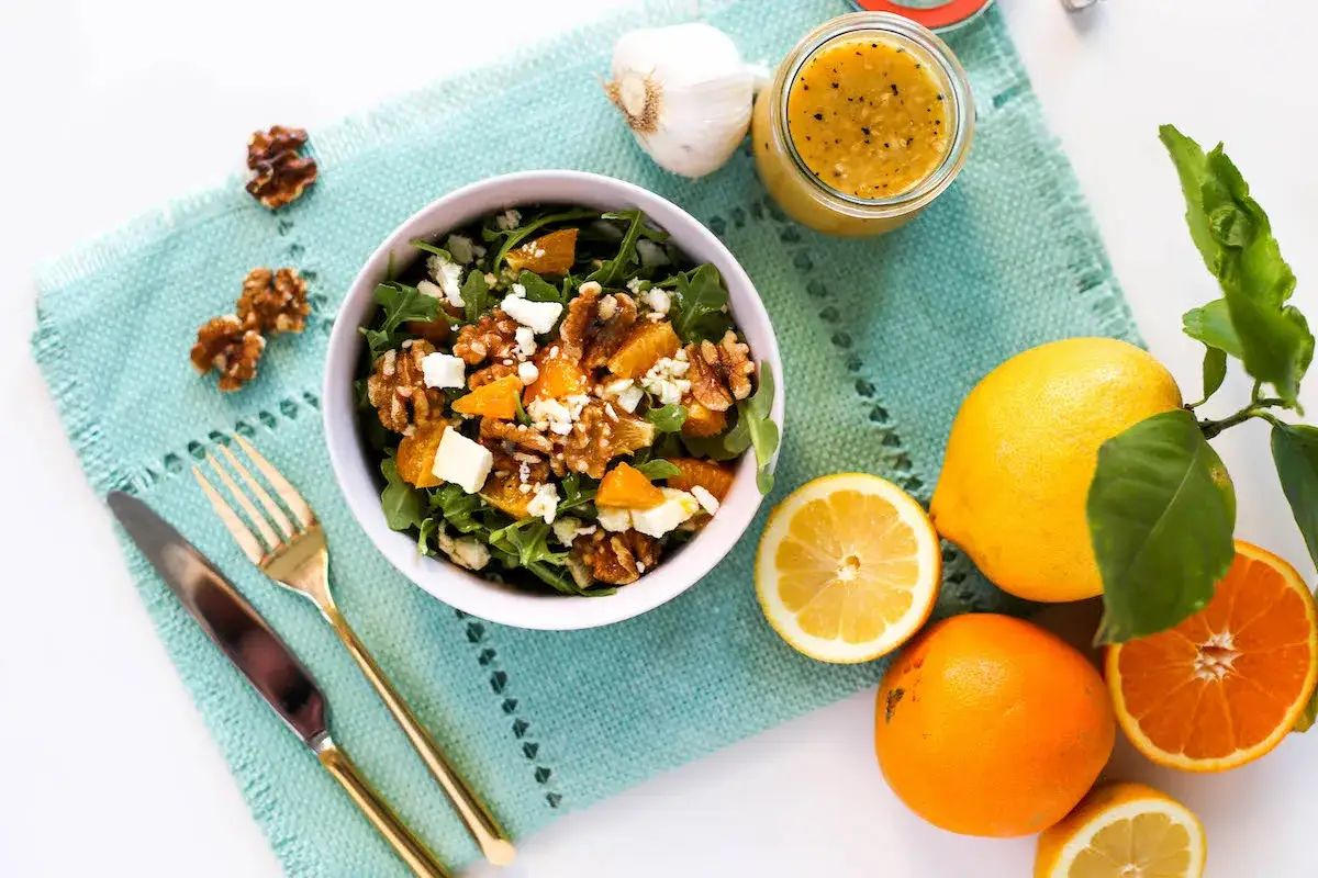 Deliciosa ensalada de rucula con naranja, nueces y queso feta. Acompañada de aderezo, limón y naranjas frescas.