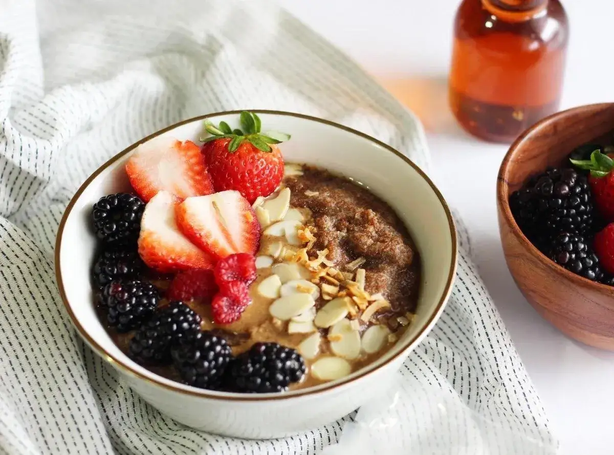 Un tazón de cereal de teff con fresas, moras, almendras y coco rallado.