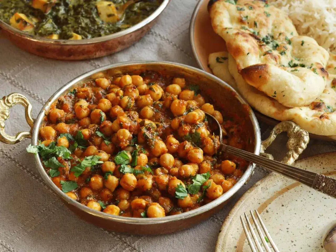 Un plato de garbanzos en salsa especiada, adornado con cilantro fresco. Descubre los garbanzos beneficios para tu salud.