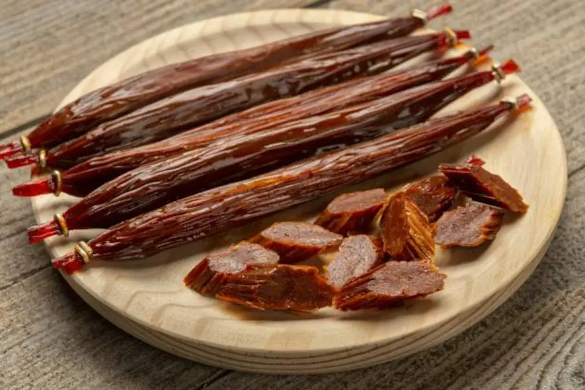 Chorizo vegano en una tabla de madera. Varios embutidos enteros y otros cortados en rodajas, listos para disfrutar.