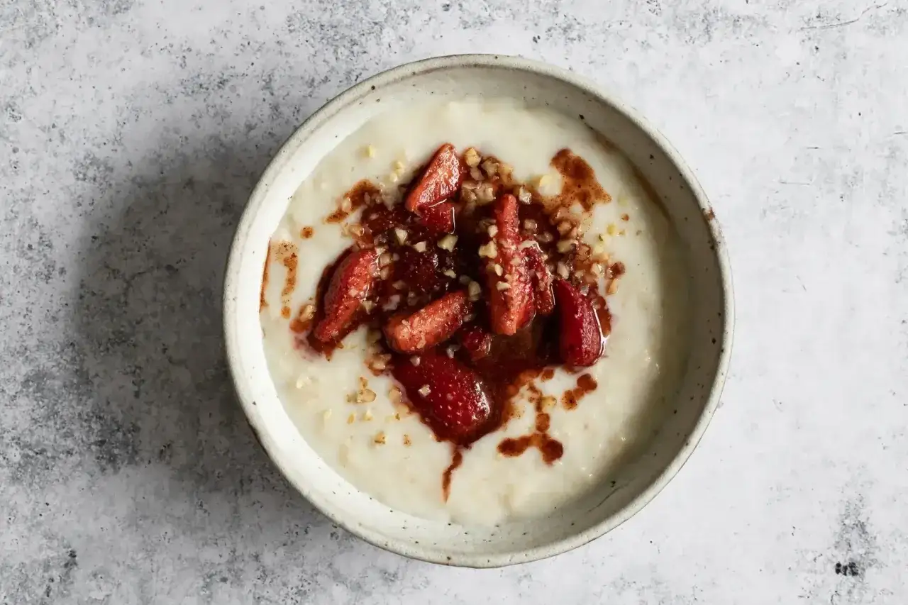 Un delicioso porridge de avena cremoso, coronado con fresas en rodajas, nueces picadas y un toque de canela.