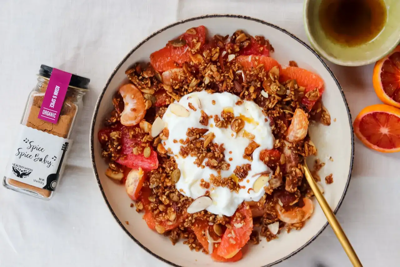 Un taz&oacute;n de granola casera con yogur, c&iacute;tricos y almendras. Una botella de especias 