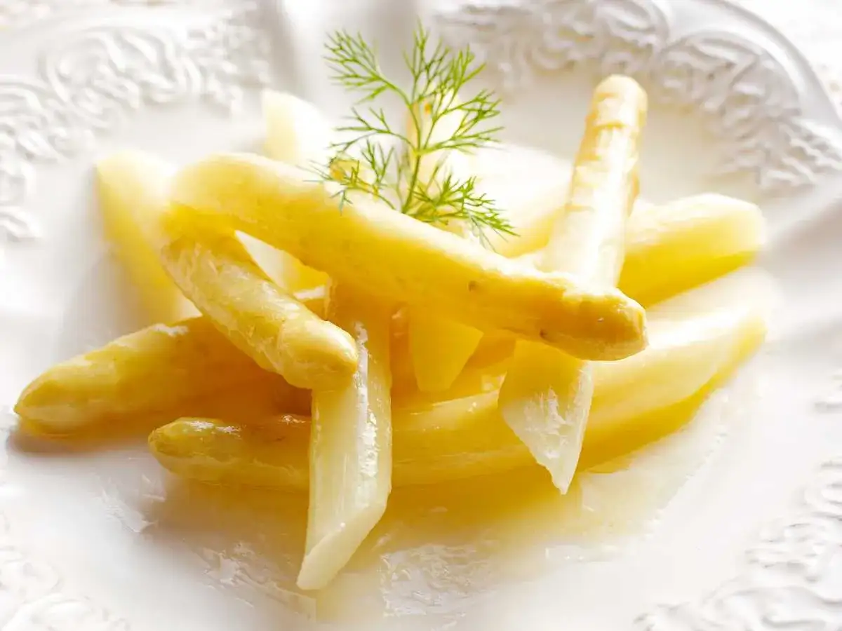 Esp&aacute;rragos blancos tiernos, reci&eacute;n cocidos y servidos en un plato blanco con un toque de eneldo. Perfectos para cocer esparragos blancos.