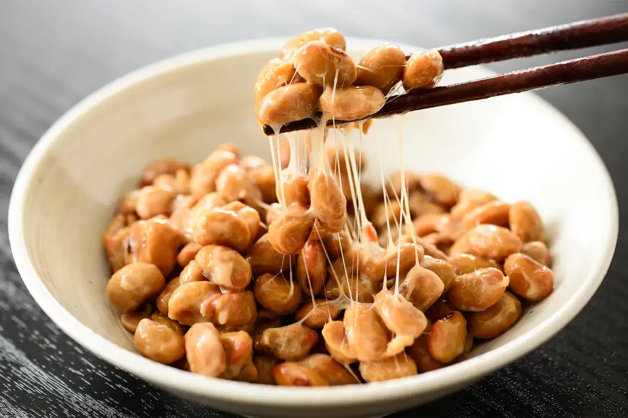 Nattokinase que es: frijoles de soja fermentados con hilos pegajosos, listos para comer.