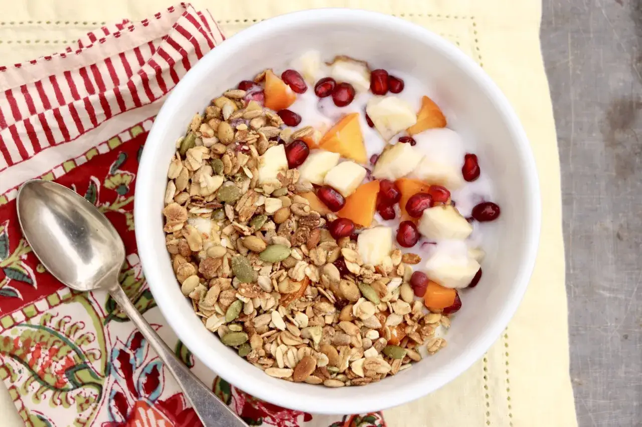 Un tazón de muesli casero con yogur, plátano, granada y albaricoque.