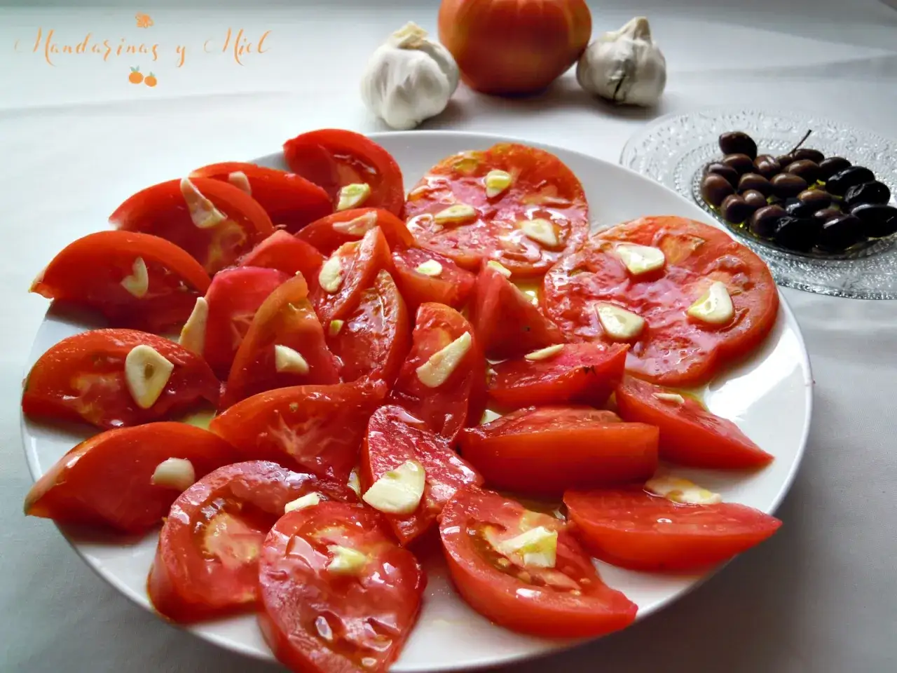Un plato de tomate ali&ntilde;ado con ajo y aceite de oliva, listo para disfrutar.
