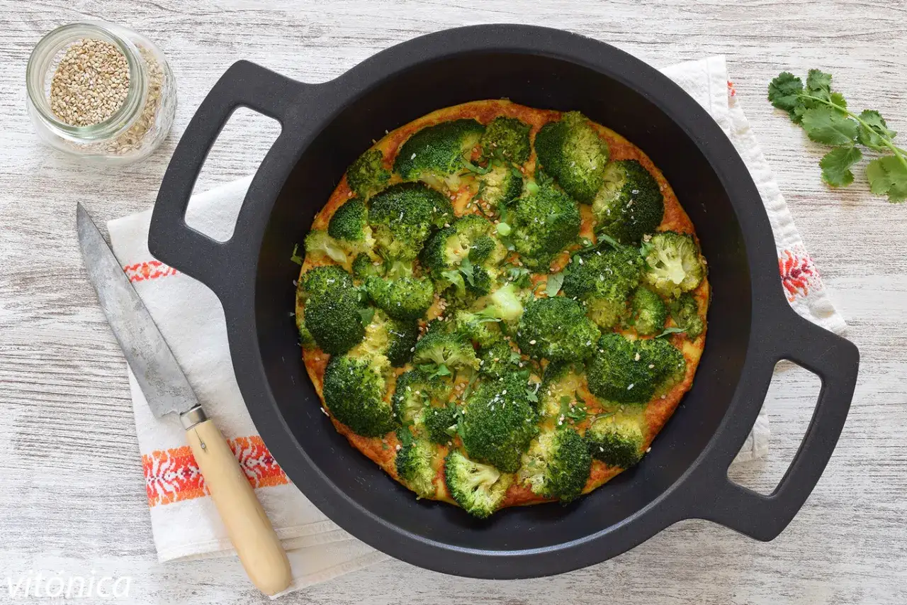 Tortilla de br&oacute;coli reci&eacute;n hecha, adornada con semillas de s&eacute;samo y perejil, lista para servir.
