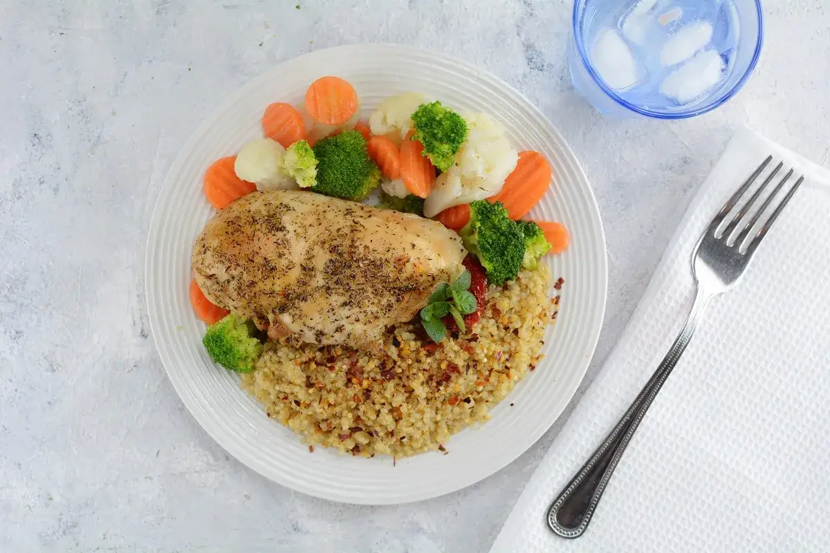 Pechuga de pollo sazonada sobre cama de quinoa con br&oacute;coli, zanahoria y coliflor al vapor. Un plato saludable y delicioso.