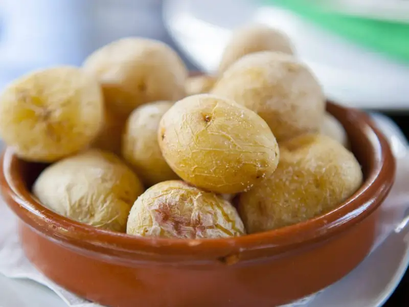 Papas arrugadas en cuenco de barro, un ejemplo del valor nutricional patata, con su piel salada y arrugada.