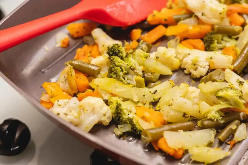 Coliflor al ajillo salteada con brócoli, zanahoria y judías verdes en una sartén, lista para servir.